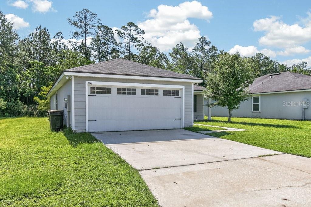 A detached garage with a white door and gray siding sits on a grassy lot — 7082 PLYMOUTH GROVE COURT, JACKSONVILLE, FL
