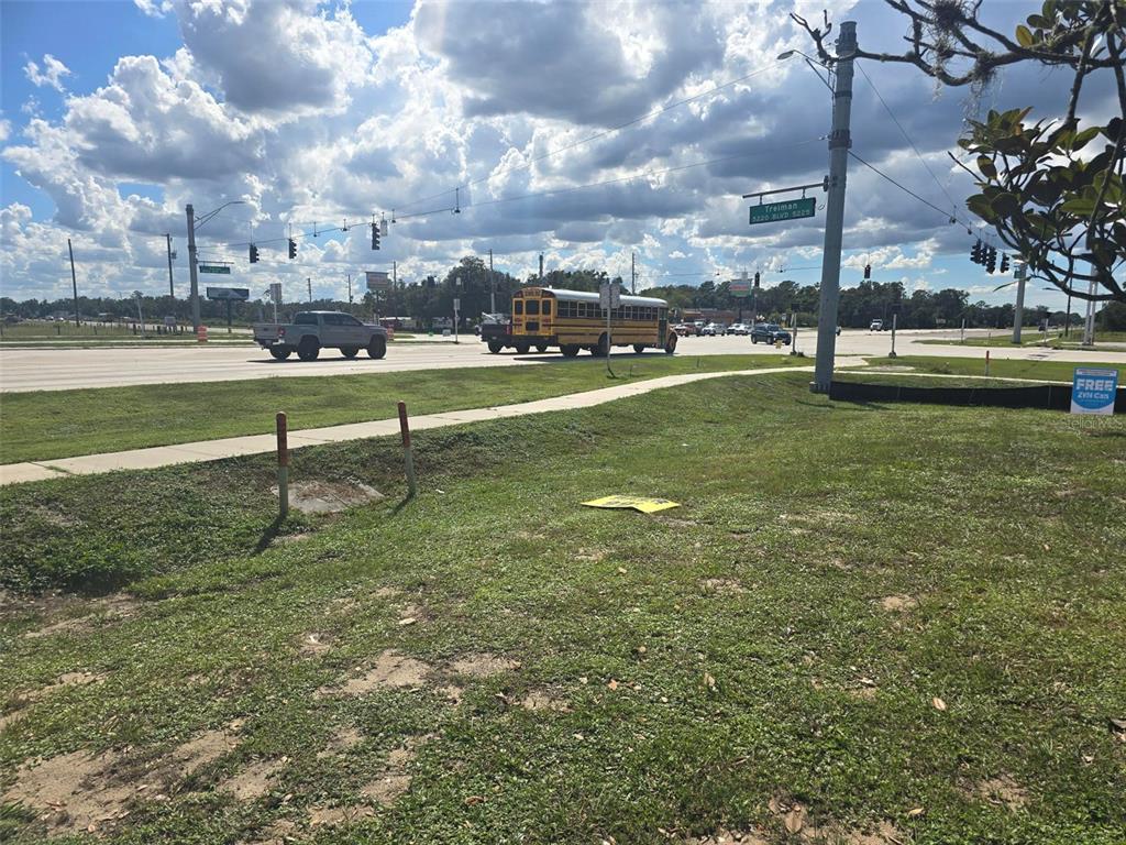 A grassy lot sits next to a sidewalk near a busy intersection with a school bus — 000 CORTEZ BOULEVARD, DADE CITY, FL