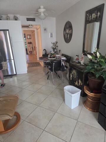 A dining area with a glass table, tile floors, and a dark cabinet with a mirror — 188 Grantham F # 188, Deerfield Beach FL 33442, DEERFIELD BEACH, FL