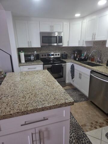 A kitchen features white cabinets, granite countertops, stainless steel appliances, and a central island — 188 Grantham F # 188, Deerfield Beach FL 33442, DEERFIELD BEACH, FL