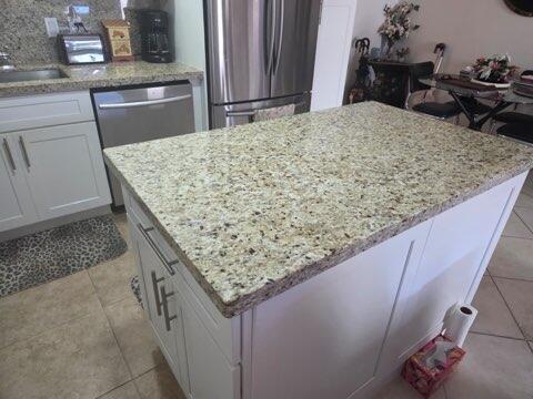 A kitchen island with a speckled granite countertop sits in front of white cabinets — 188 Grantham F # 188, Deerfield Beach FL 33442, DEERFIELD BEACH, FL