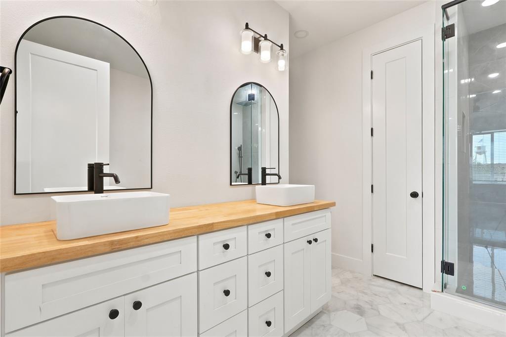 A bathroom features a double vanity with a wood countertop, white cabinets, and arched mirrors — 2138 W NASSAU STREET UNIT 2, TAMPA, FL