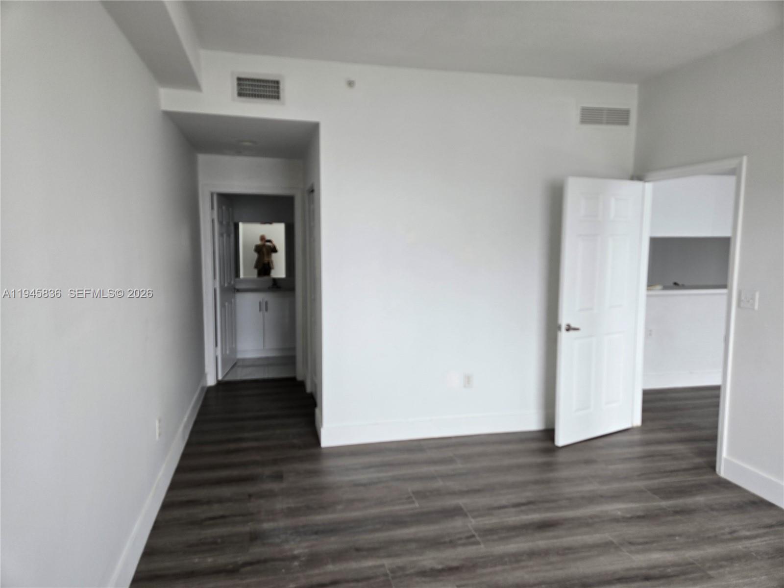 An empty room features white walls, dark wood-look flooring, and two open doorways — 275 NE 18th St # 503, Miami FL 33132, MIAMI, FL