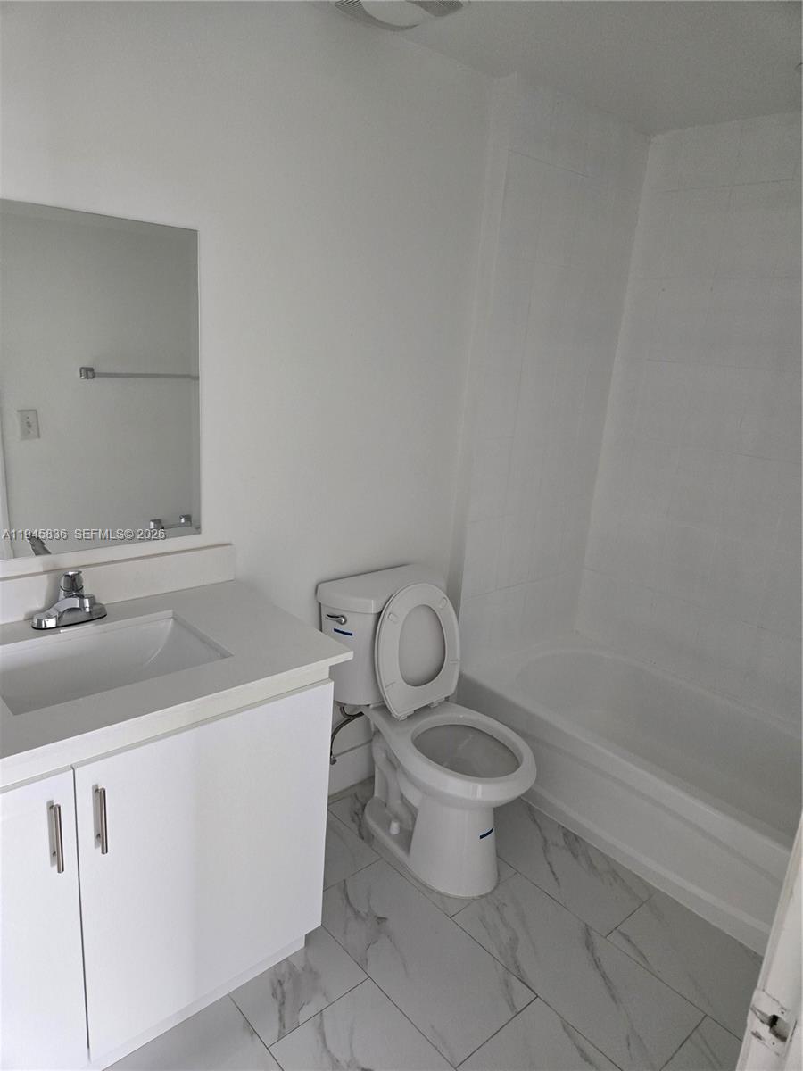 A bathroom features a white vanity, a toilet, and a shower-tub combo with tiled floors — 275 NE 18th St # 503, Miami FL 33132, MIAMI, FL