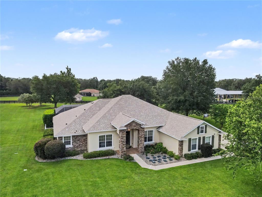 An aerial view of a single-story house with a stone facade and a shingled roof — 12913 COUNTY ROAD 104B, OXFORD, FL