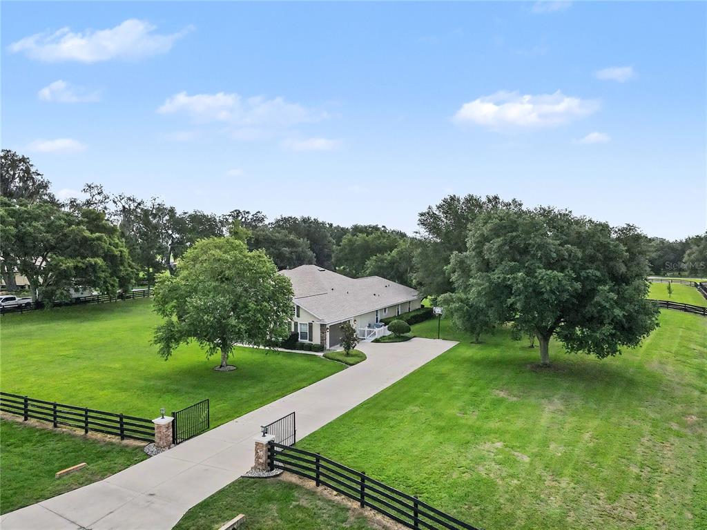 An aerial view shows a house with a long driveway and fenced yard — 12913 COUNTY ROAD 104B, OXFORD, FL