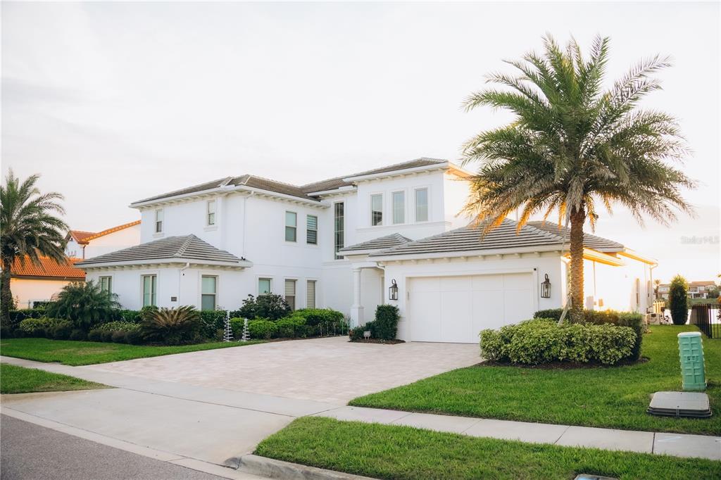 A two-story white house with a tile roof, a paved driveway, and a palm tree — 15505 SHOREBIRD LANE, WINTER GARDEN, FL
