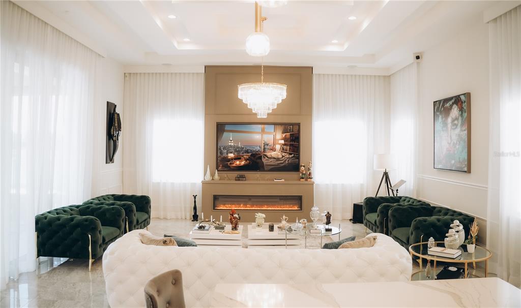 A living room features a white tufted sofa, green velvet armchairs, and a fireplace — 15505 SHOREBIRD LANE, WINTER GARDEN, FL