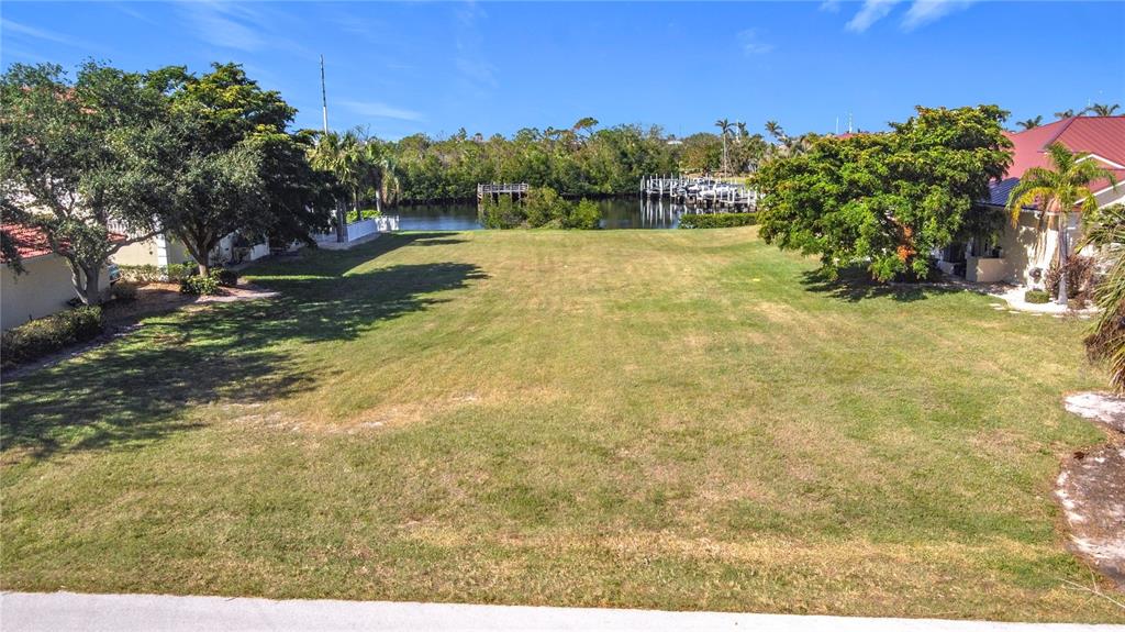 A vacant grassy lot sits between two houses with a view of a canal — 3227 PURPLE MARTIN DRIVE, PUNTA GORDA, FL