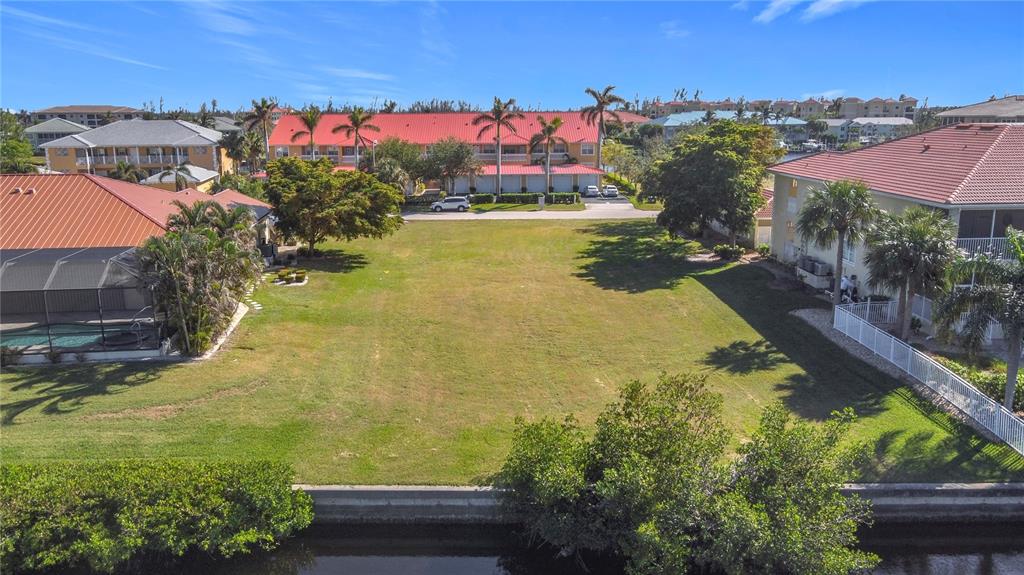 An aerial view shows a vacant grassy lot situated between two residential buildings near water — 3227 PURPLE MARTIN DRIVE, PUNTA GORDA, FL