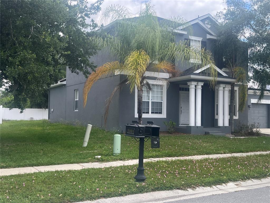 A two-story gray house with white trim, columns, and a palm tree in the front yard — 2981 MARSHFIELD PRESERVE WAY, KISSIMMEE, FL