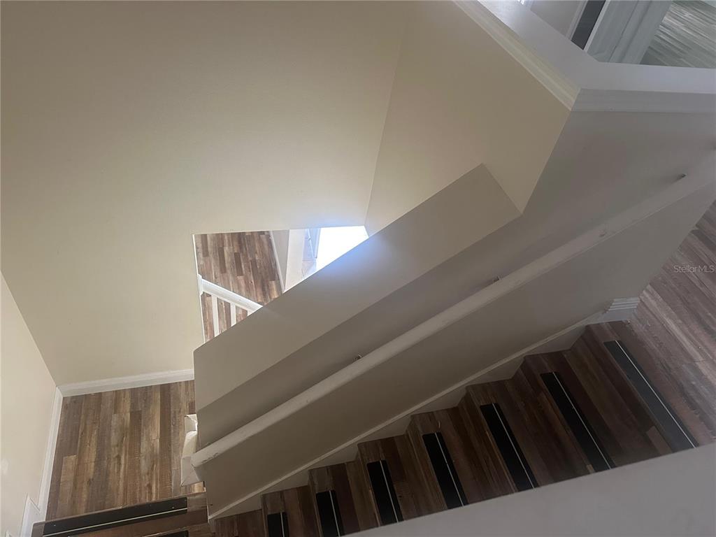 A high-angle view shows a staircase with wood-look flooring and white walls — 2981 MARSHFIELD PRESERVE WAY, KISSIMMEE, FL