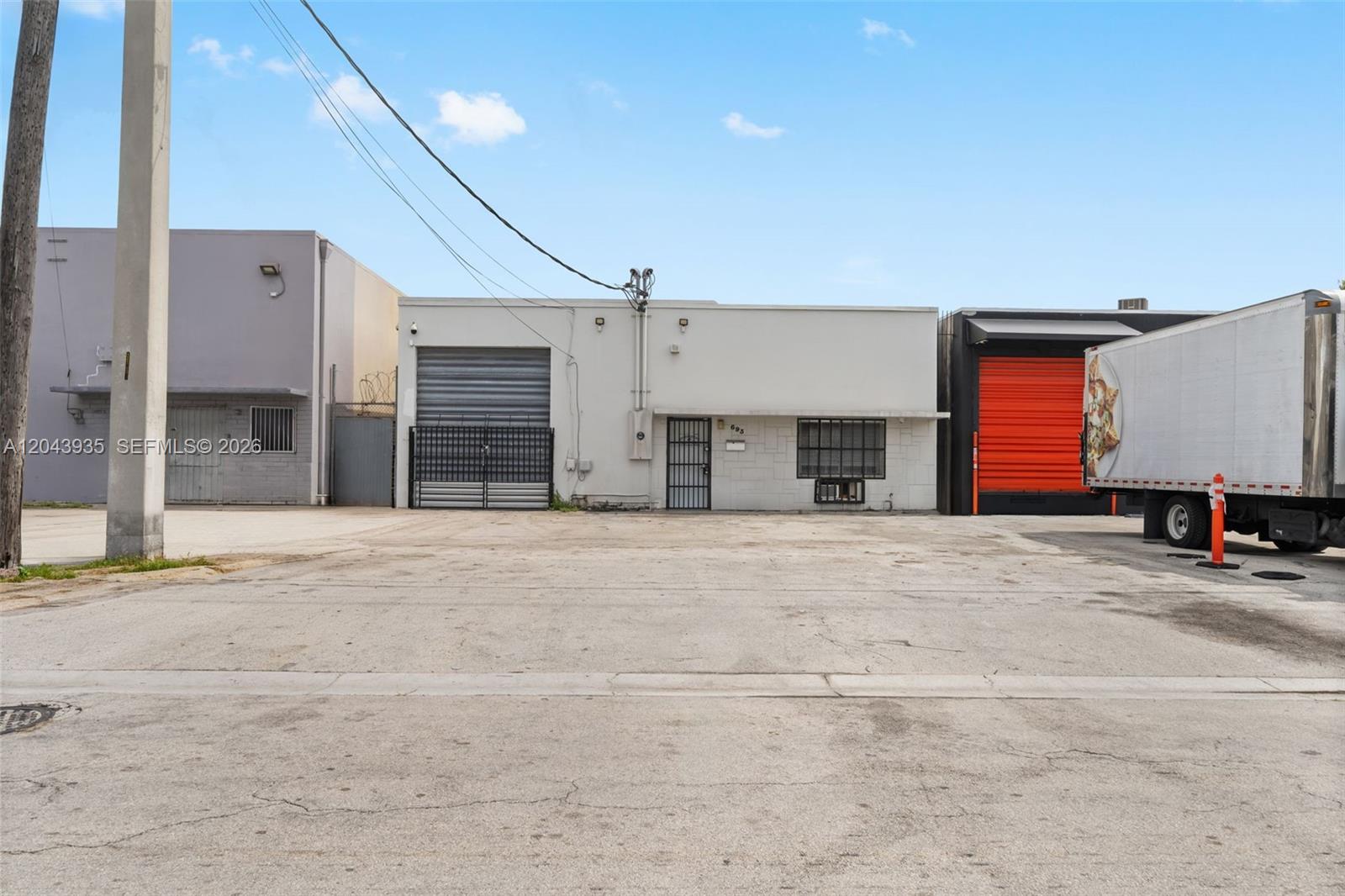 A single-story commercial building with a concrete parking lot and a parked semi-truck — 693 W 26th St, Hialeah FL 33010, HIALEAH, FL