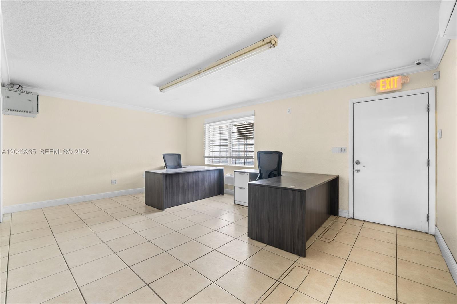 An office space features two dark wood desks, tile flooring, and an exit door — 693 W 26th St, Hialeah FL 33010, HIALEAH, FL