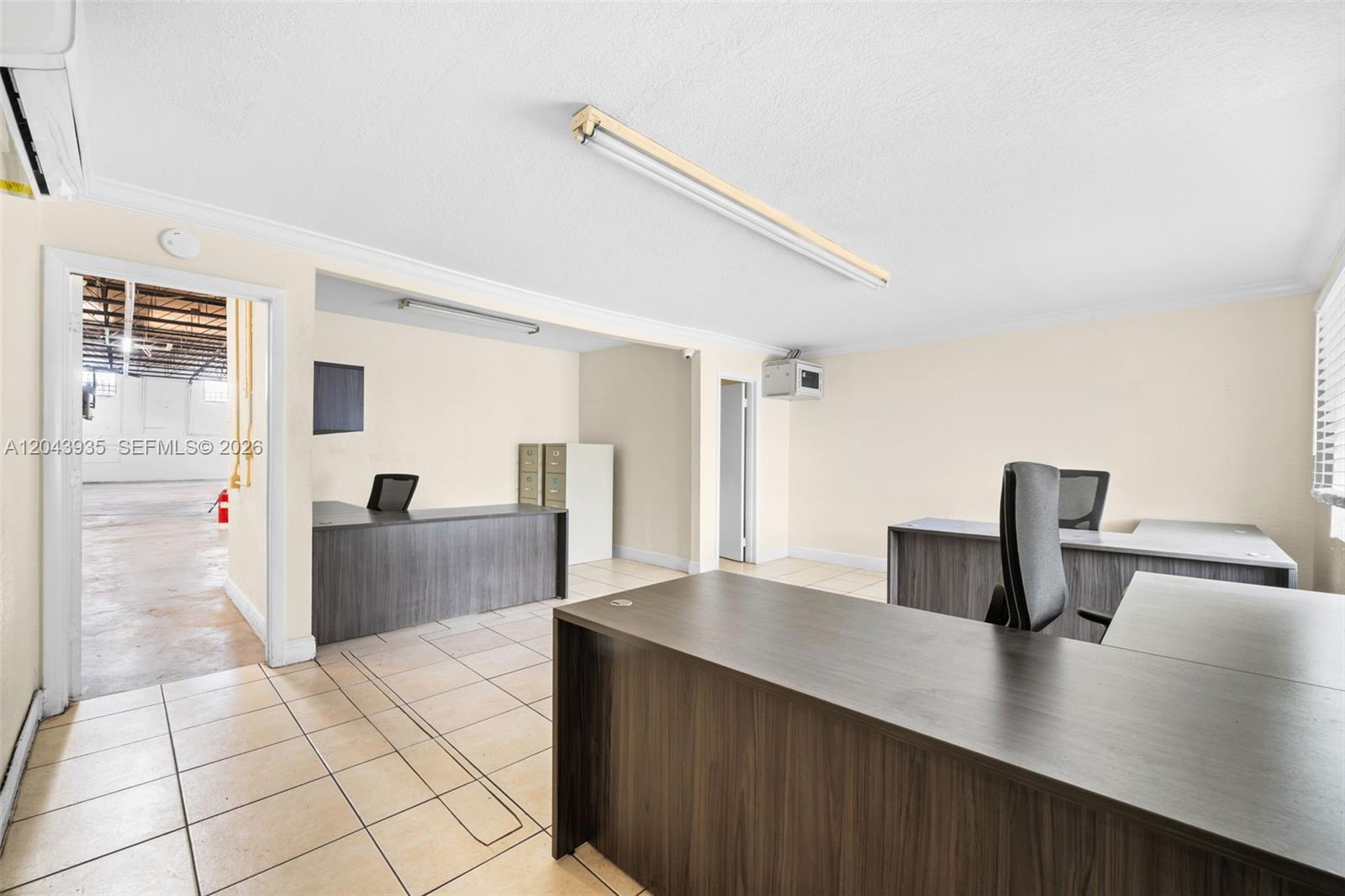 An office space features tiled floors, multiple desks, and a doorway leading to a warehouse — 693 W 26th St, Hialeah FL 33010, HIALEAH, FL