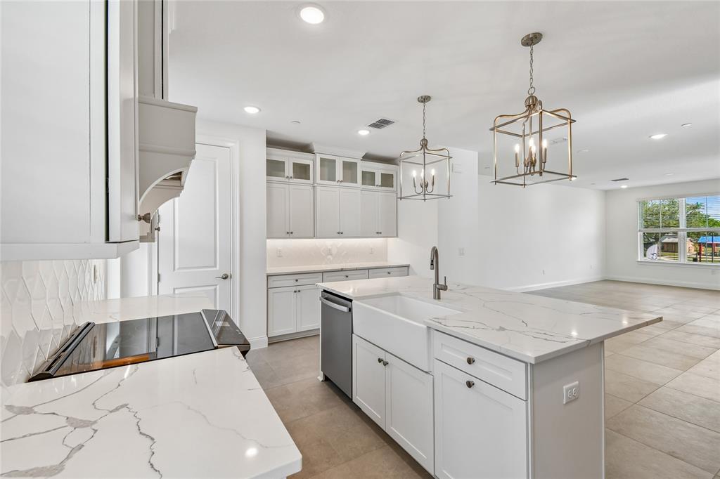 A modern kitchen features white cabinetry, marble-look countertops, a farmhouse sink, and two pendant lights — 222 PASQUALA, OVIEDO, FL