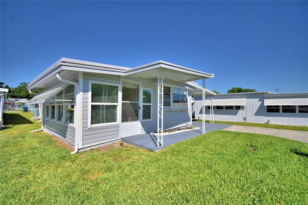 A light gray mobile home with a covered porch and white trim sits on grass — 117 HOLIDAY LANE, AUBURNDALE, FL