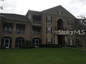 A three-story tan apartment building with screened-in ground floor patios and upper-level balconies — 14238 FREDRICKSBURG DRIVE UNIT 317, ORLANDO, FL