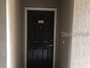 A black front door with a silver handle is set within a beige stucco entryway — 14238 FREDRICKSBURG DRIVE UNIT 317, ORLANDO, FL
