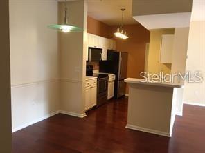 A kitchen with dark wood floors, white cabinets, stainless steel appliances, and a breakfast bar — 14238 FREDRICKSBURG DRIVE UNIT 317, ORLANDO, FL