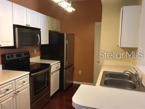 A kitchen featuring white cabinets, stainless steel appliances, and a double-basin sink — 14238 FREDRICKSBURG DRIVE UNIT 317, ORLANDO, FL