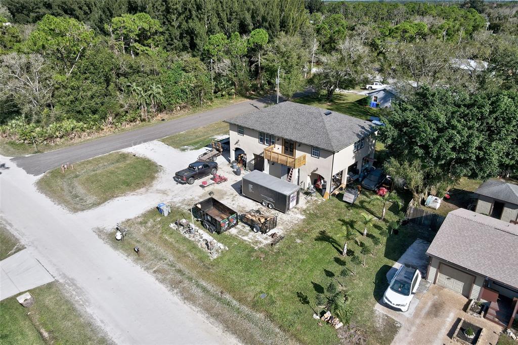 An aerial view shows a two-story house with a wooden balcony, trailers, and parked vehicles — 45 S PINE STREET, FELLSMERE, FL