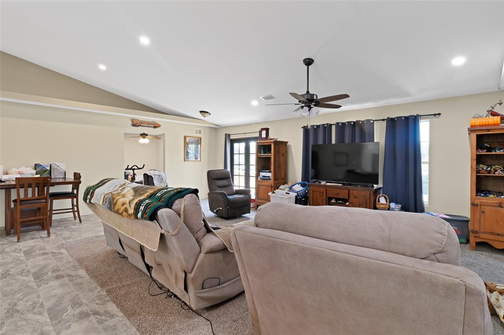 A living room features a vaulted ceiling, a ceiling fan, and a large television console — 45 S PINE STREET, FELLSMERE, FL