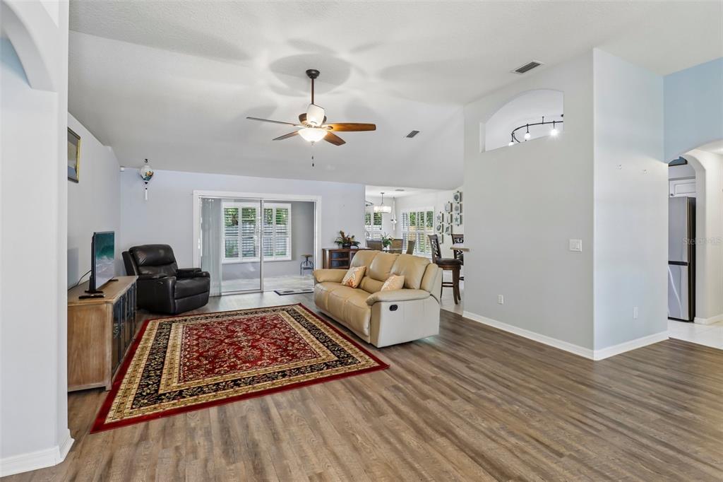 A living room with a beige sofa, red area rug, and wood-look flooring — 7 PRAIRIEVIEW LANE, ORMOND BEACH, FL