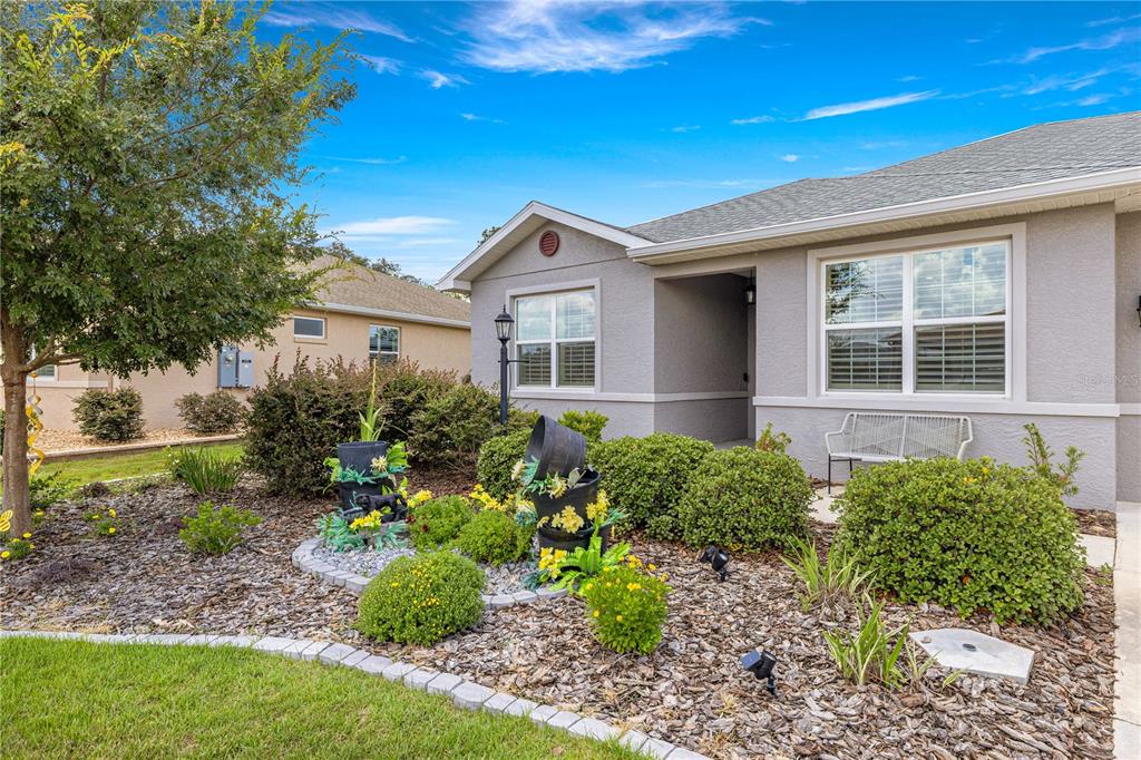 A gray stucco house features a landscaped front yard with a stone-bordered garden bed — 8847 SW 104TH CIRCLE, OCALA, FL