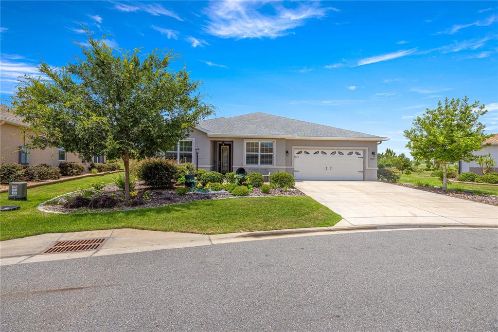 A single-story house with a beige exterior, a two-car garage, and a landscaped front yard — 8847 SW 104TH CIRCLE, OCALA, FL