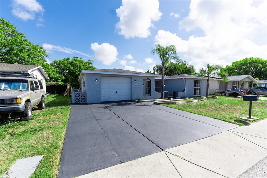 A single-story house with a gray exterior, a one-car garage, and a paved driveway — 7015 POTOMAC DRIVE, PORT RICHEY, FL