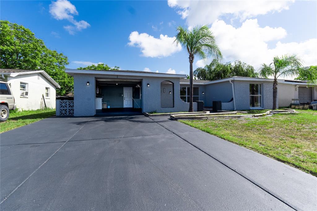 A single-story house with a gray stucco exterior, a flat roof, and a paved driveway — 7015 POTOMAC DRIVE, PORT RICHEY, FL