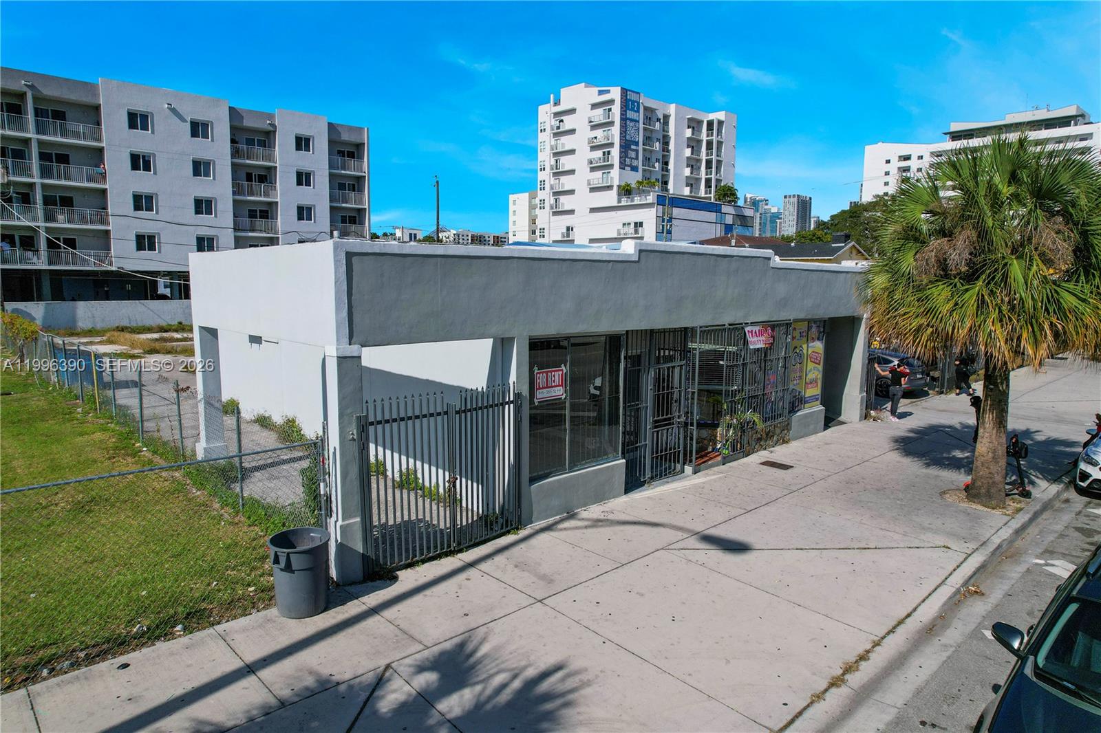 A single-story commercial building with a gray facade sits next to a fenced vacant lot — 727 W Flagler St, Miami FL 33130, MIAMI, FL