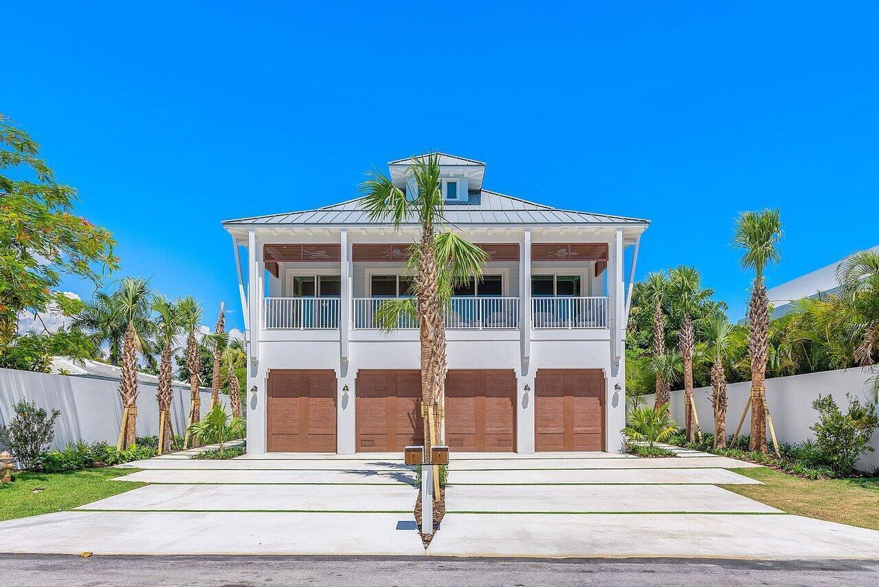 A two-story white house features four brown garage doors and a second-floor balcony — 909 Bond Way, Delray Beach FL 33483, DELRAY BEACH, FL