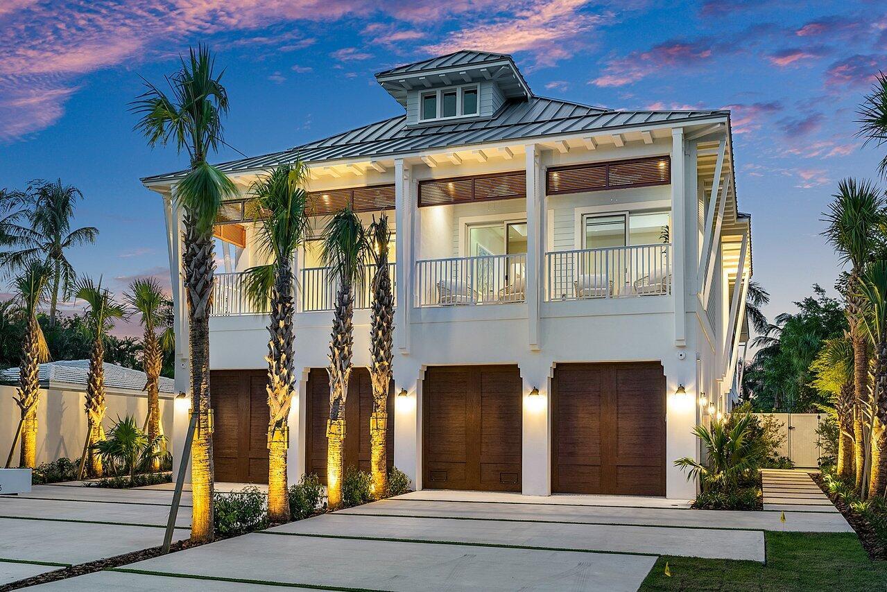 A two-story white house with a metal roof, balcony, and three dark wood garage doors — 909 Bond Way, Delray Beach FL 33483, DELRAY BEACH, FL