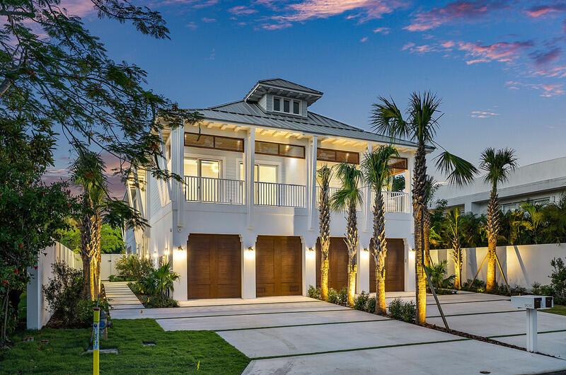 A two-story white house with a metal roof, wooden garage doors, and palm trees — 909 Bond Way, Delray Beach FL 33483, DELRAY BEACH, FL