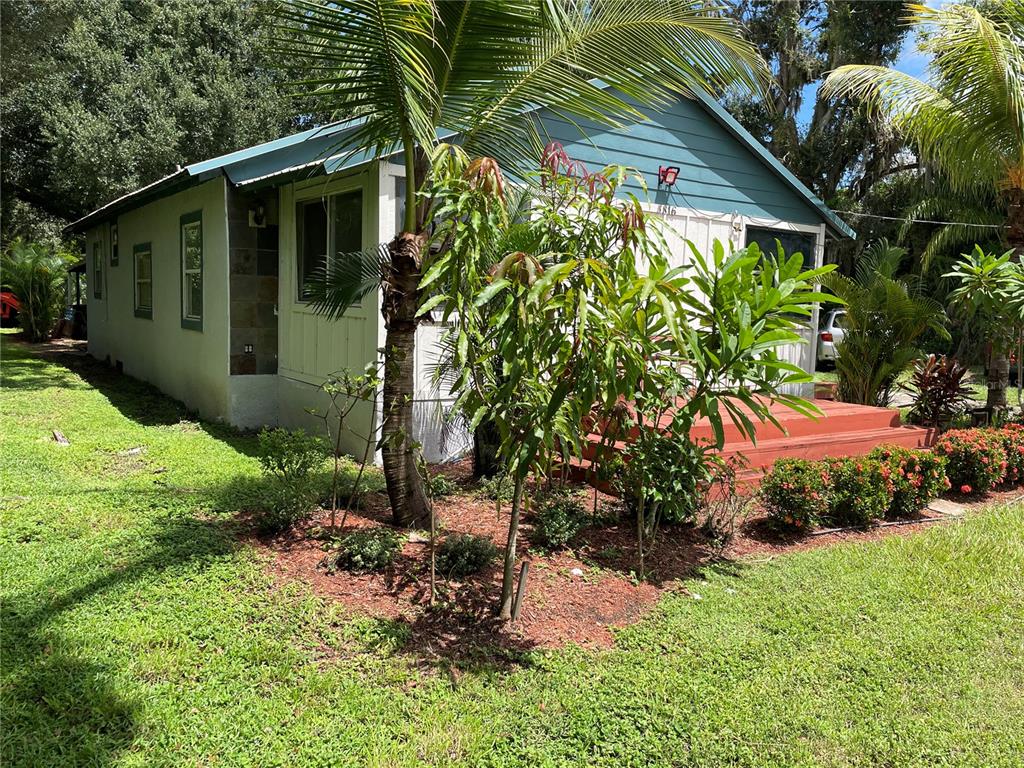 A single-story house with blue siding, a red front deck, and lush landscaping — 3816 LONE OAK ROAD, PLANT CITY, FL