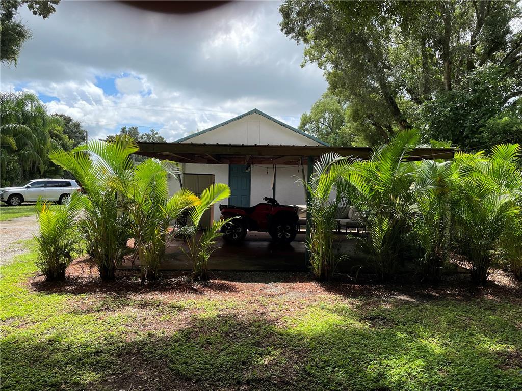 A covered patio with a red ATV sits in front of a small white house — 3816 LONE OAK ROAD, PLANT CITY, FL