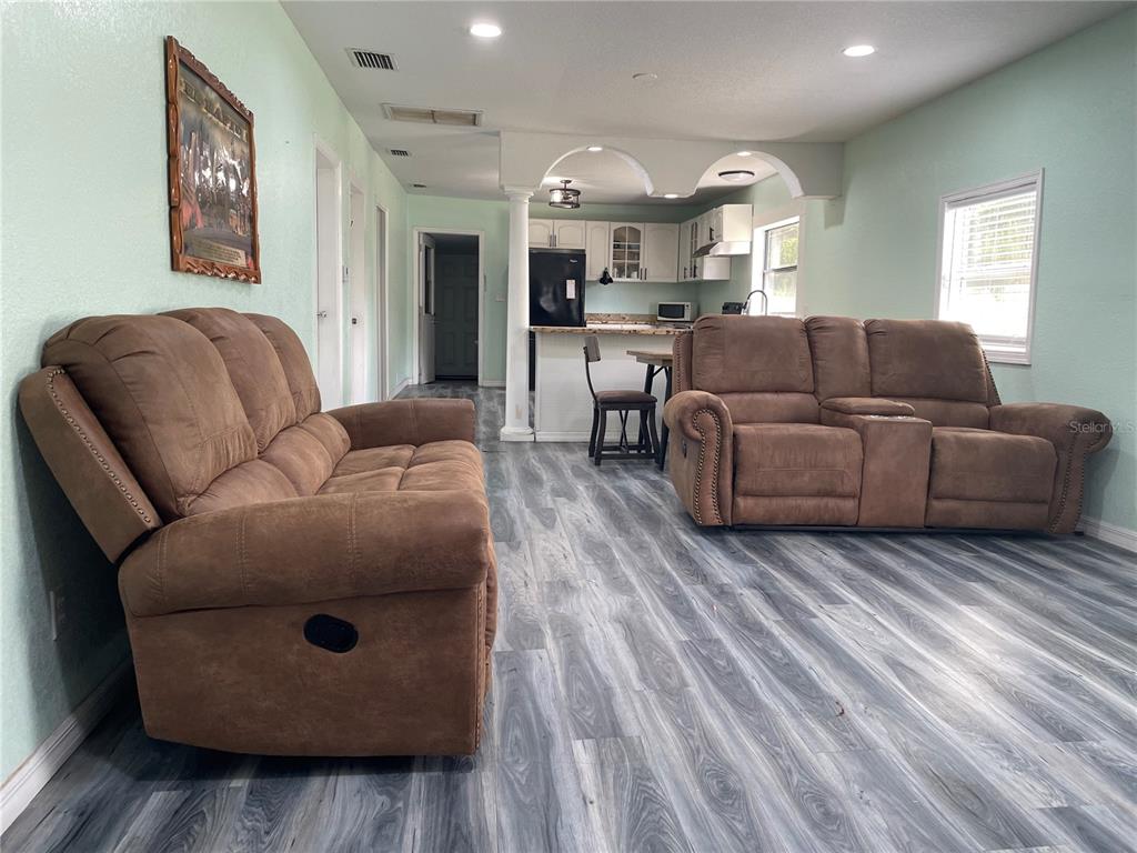 A living room with two brown reclining sofas, light green walls, and gray wood-look flooring — 3816 LONE OAK ROAD, PLANT CITY, FL