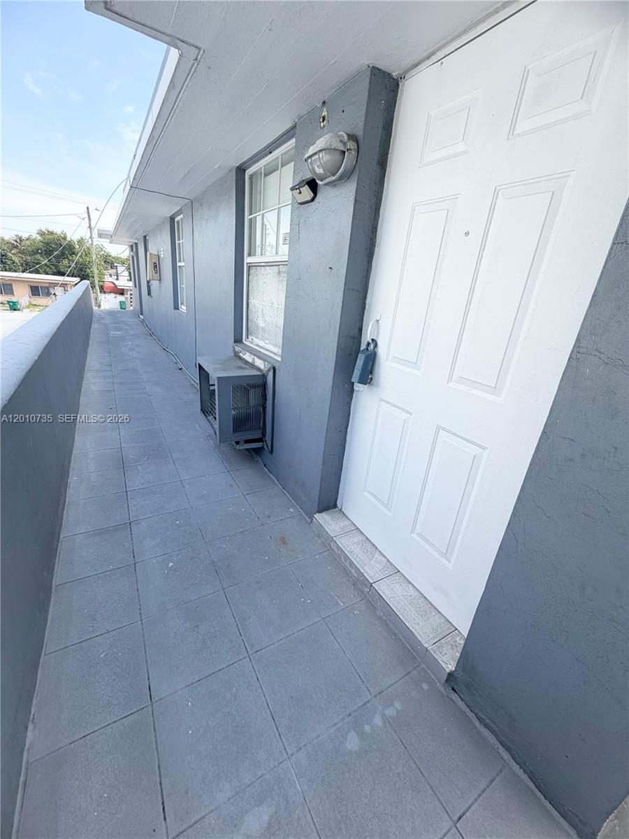 A gray exterior walkway features a white door, a window, and a wall-mounted air conditioner — 2736 SW 22nd STREET # 2, Miami FL 33133, MIAMI, FL