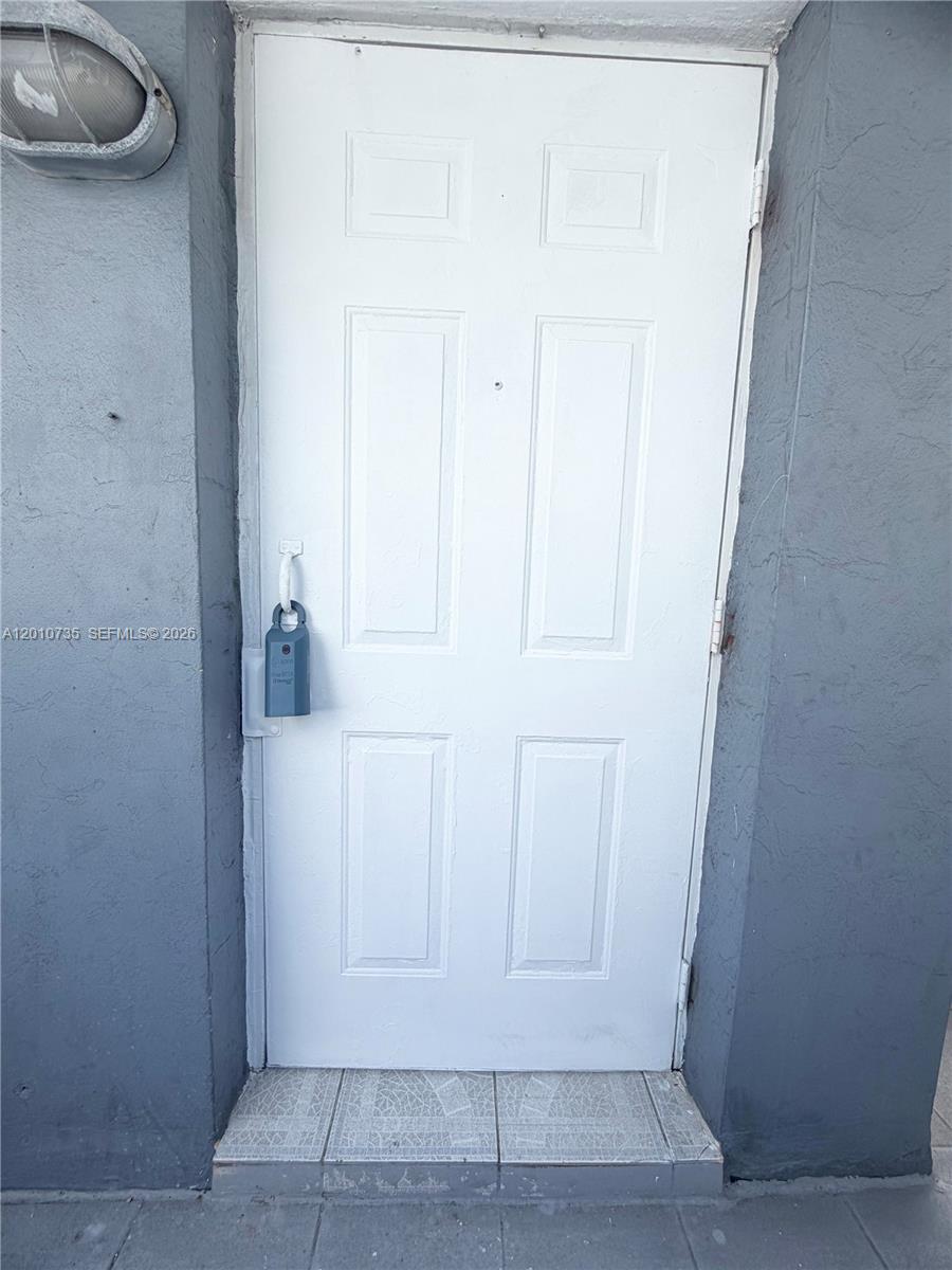 A white six-panel door with a padlock is set within a gray stucco exterior wall — 2736 SW 22nd STREET # 2, Miami FL 33133, MIAMI, FL