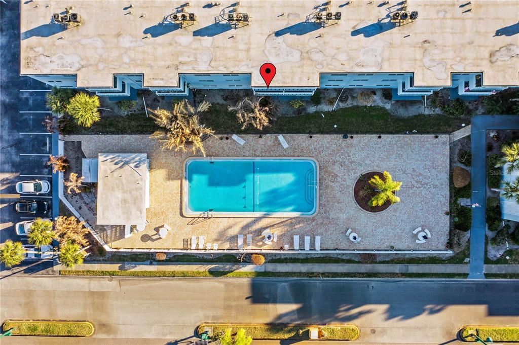 An aerial view shows a rectangular swimming pool surrounded by a paved deck and building — 221 COLUMBIA DRIVE UNIT 340, CAPE CANAVERAL, FL