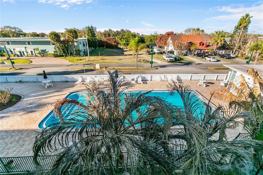 An elevated view of a swimming pool and patio area with palm trees and buildings — 221 COLUMBIA DRIVE UNIT 340, CAPE CANAVERAL, FL