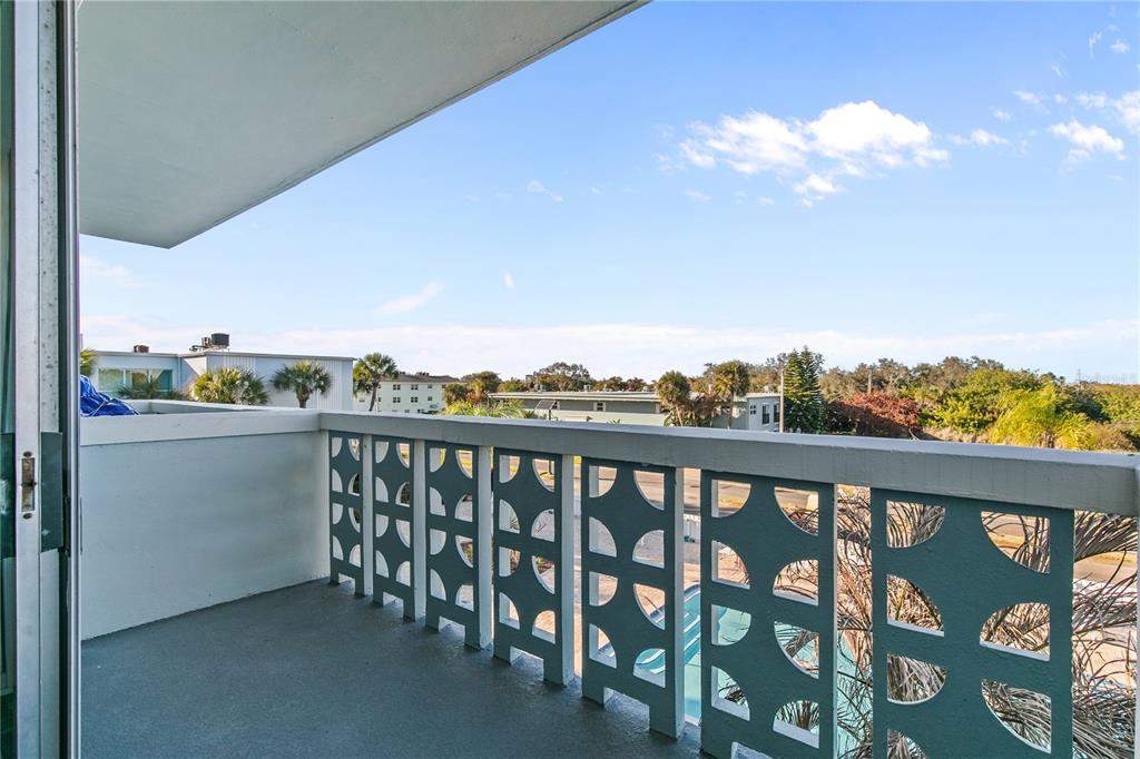 A balcony with a decorative teal railing overlooks a residential area under a blue sky — 221 COLUMBIA DRIVE UNIT 340, CAPE CANAVERAL, FL