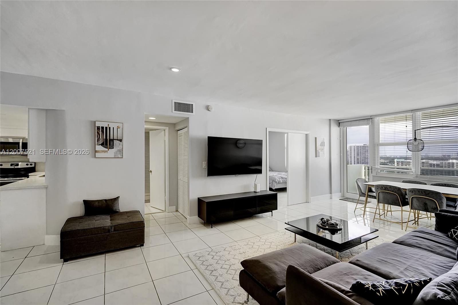 A modern living room features white tile floors, a wall-mounted television, and a dining area — 3725 S Ocean Dr # 1519, Hollywood FL 33019, HOLLYWOOD, FL