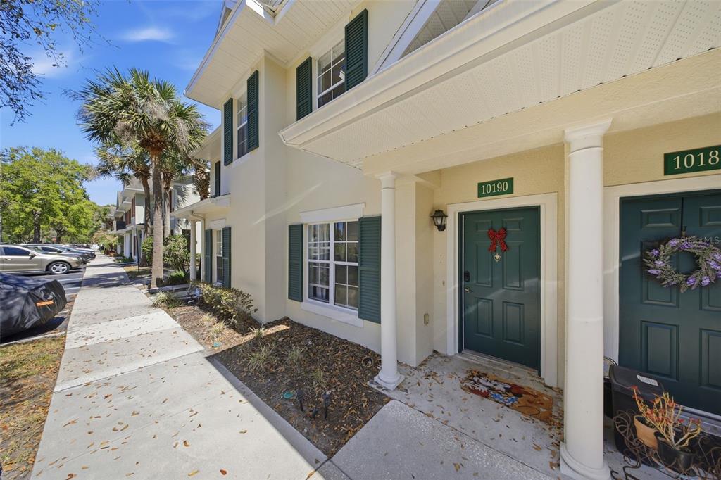 A two-story townhouse exterior with a green front door, white columns, and a sidewalk — 10190 REGENT PARK DRIVE UNIT 2103, ORLANDO, FL