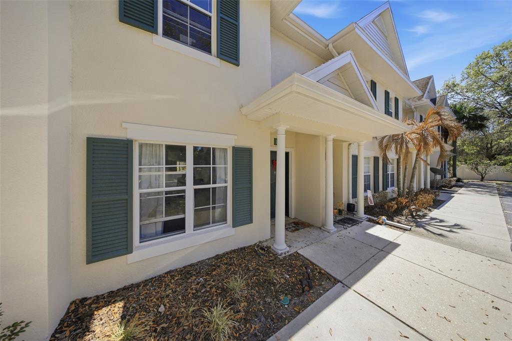 A two-story townhouse exterior features a covered entryway with white columns and green shutters — 10190 REGENT PARK DRIVE UNIT 2103, ORLANDO, FL