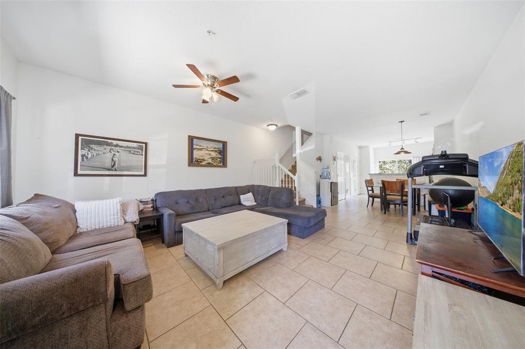 A living room with tile floors, a sectional sofa, a coffee table, and a treadmill — 10190 REGENT PARK DRIVE UNIT 2103, ORLANDO, FL