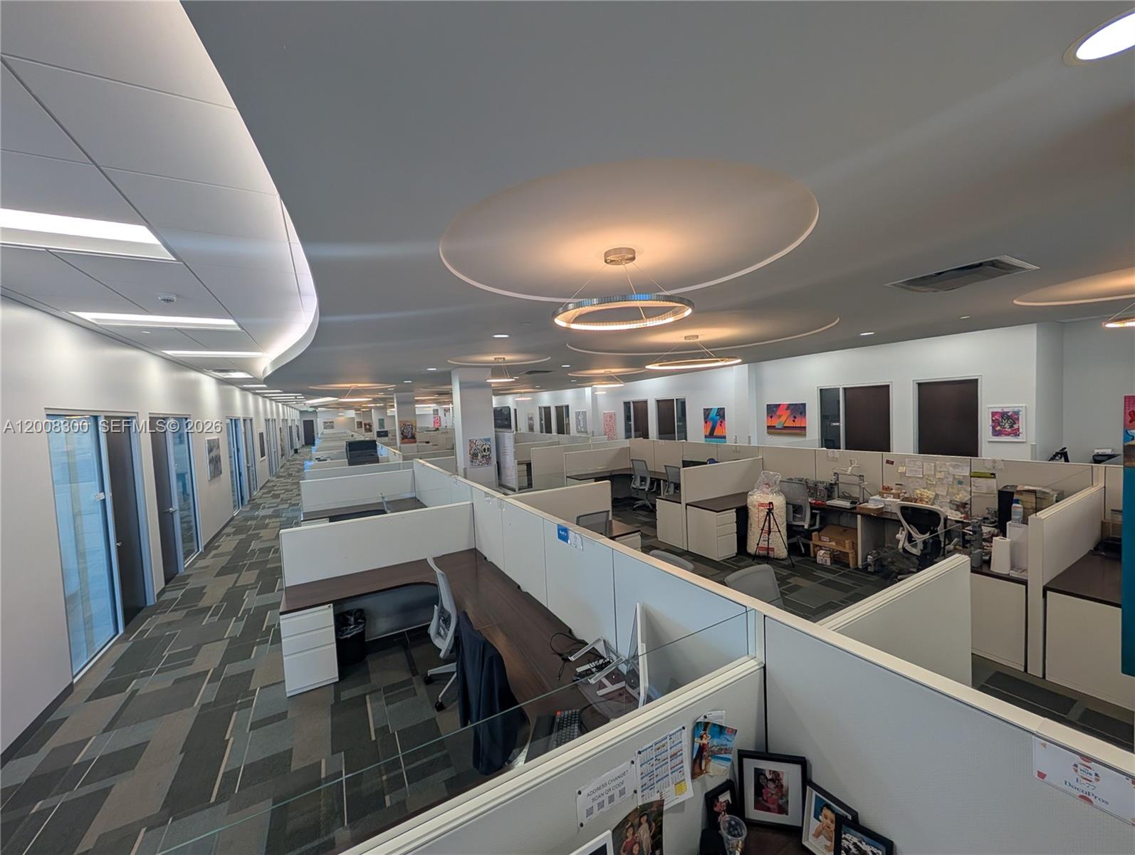 An open-plan office space features rows of cubicles, patterned carpet, and circular ceiling light fixtures — 1501 Biscayne Blvd, Miami FL 33132, MIAMI, FL