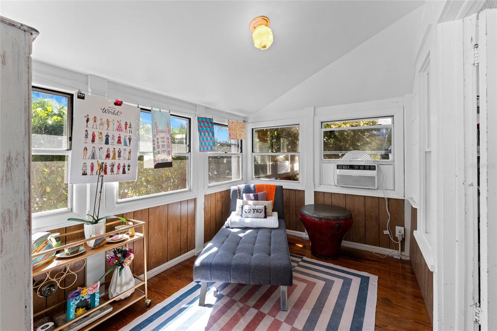 A sunroom features wood-paneled walls, a gray chaise lounge, and a striped area rug — 783 30TH AVENUE N, ST PETERSBURG, FL
